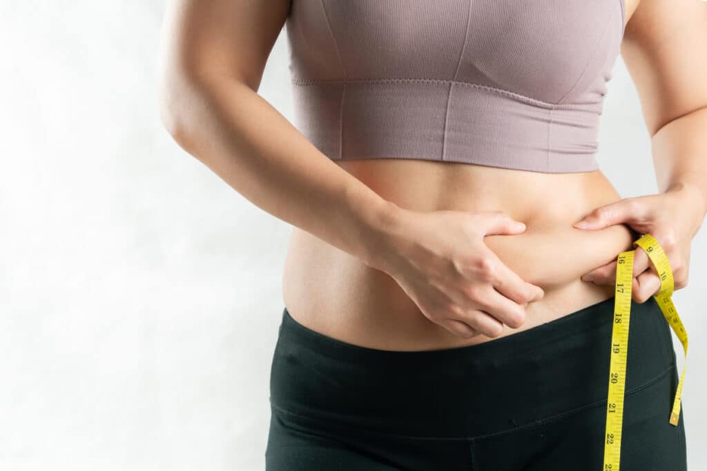 Woman pinching the excess fat on her stomach, suffering from either obesity or lipedema and needing treatment. Woman pinching the excess fat on her stomach, suffering from either obesity or lipedema and needing treatment.